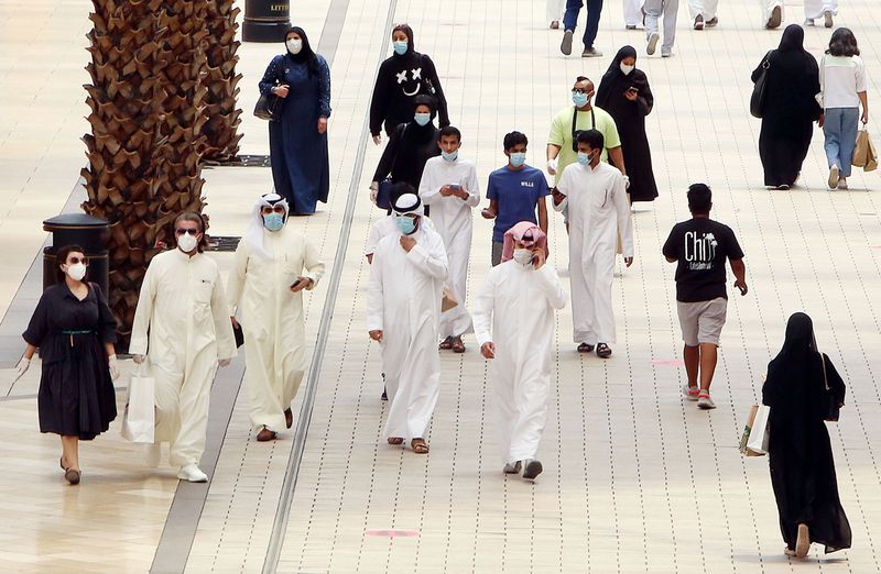 Kuwaitis wearing face masks walk inside