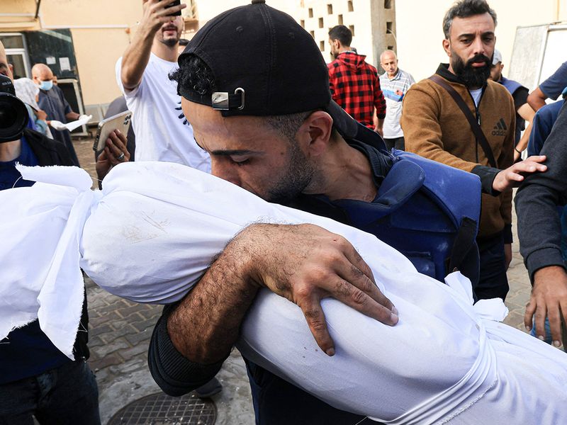 Graphic content: Palestinian cameraman Mohammed Alaloul holds the shrouded body of one of his children killed in an Israeli strike on the Al-Maghazi refugee camp in Deir Balah in the central Gaza Strip, in front of Al Quds hospital. 