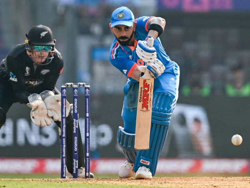 India's Virat Kohli plays a shot as New Zealand's Tom Latham (L) watches during the 2023 ICC Men's Cricket World Cup one-day international (ODI) first semi-final match between India and New Zealand at the Wankhede Stadium in Mumbai on November 15, 2023