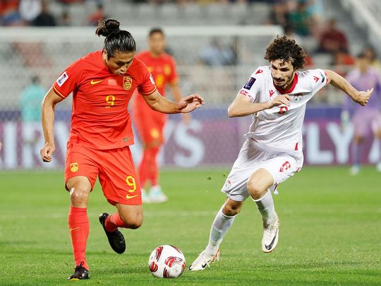 Tajikistan's defender Vakhdat Khanonov (right) vies for the ball against China's forward Zhang Yuning